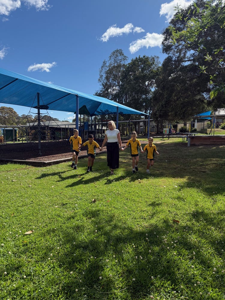 Principal walking in playground with four students.
